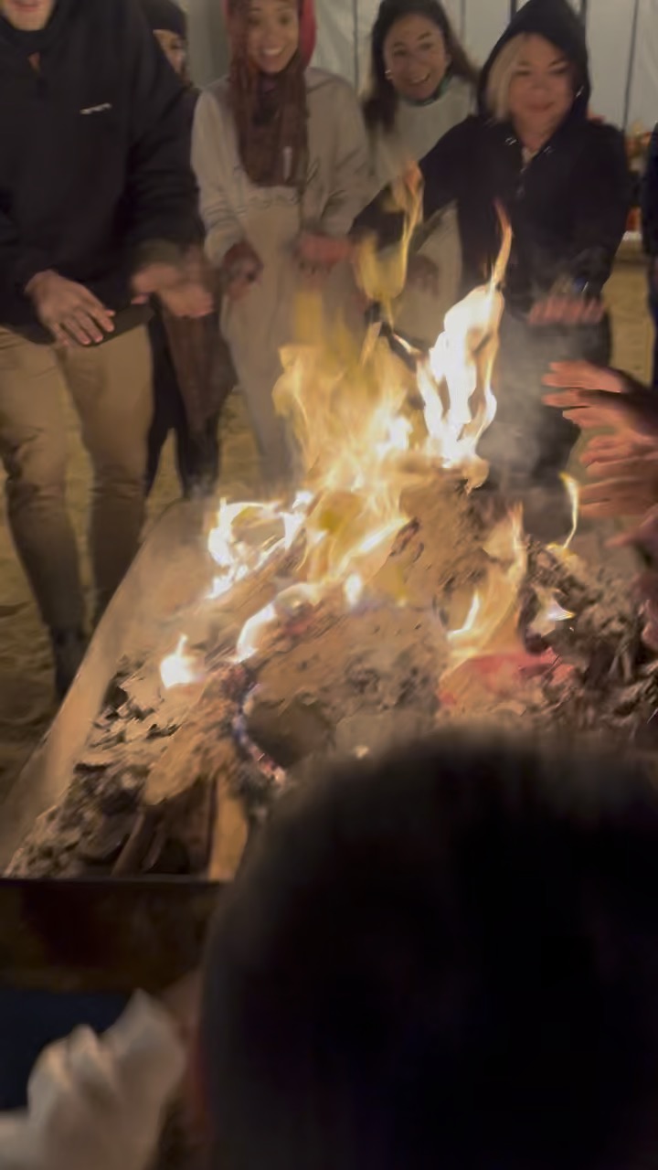 Gruppen värmer sig vid lägerelden i ökenlägret