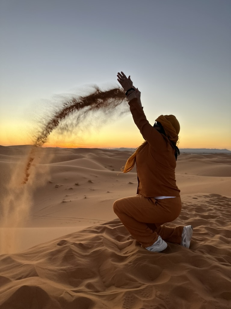 En resenär kastar sand i luften på dynerna