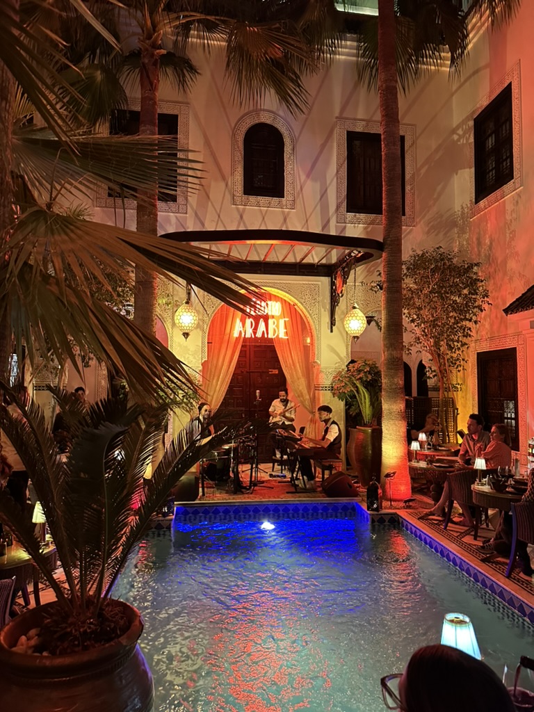 Innergård med pool, palmer och livemusik i Marrakech på kvällen