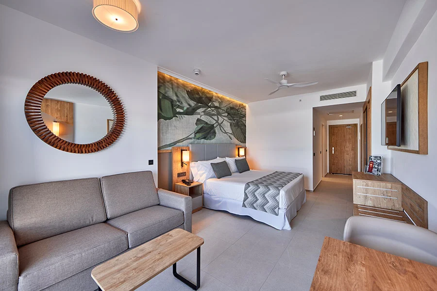 Rum på Riu Palace Mauritius med dubbelsäng, soffa och en rund spegel