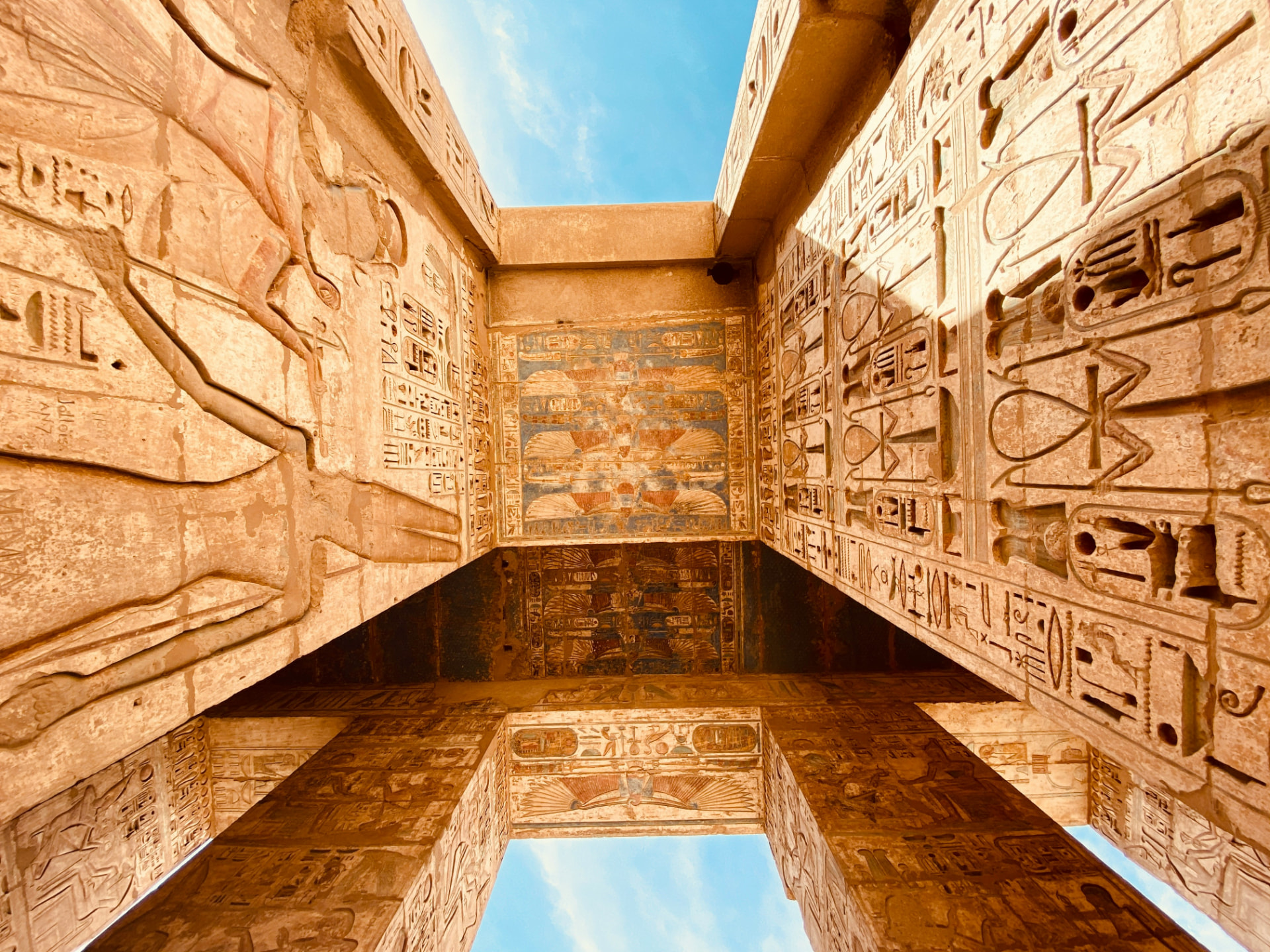 Färgglada hieroglyfer och reliefer under pelarna i ett egyptiskt tempel, sedda uppifrån