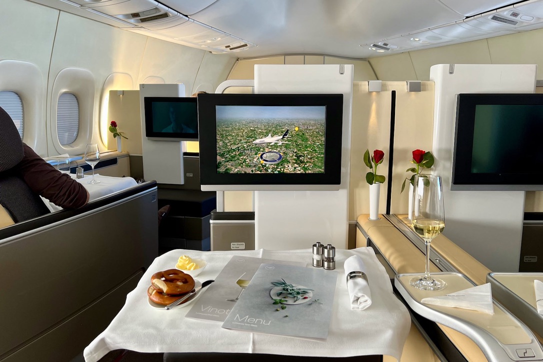 Lufthansa First Class-kabin med dukat bord och rosor