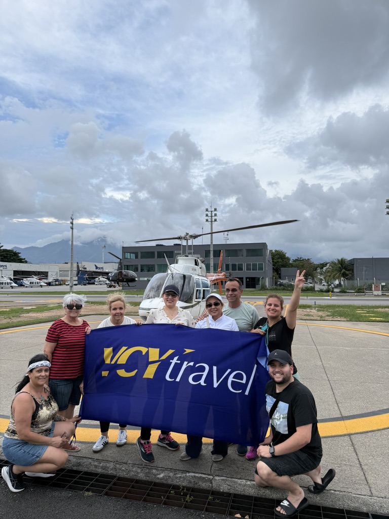 Gruppen framför en helikopter inför en flygtur över Rio de Janeiro, med VCY Travel-flaggan